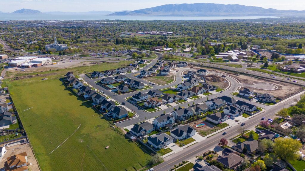 Aerial view of a residential neighborhood featuring houses, with a majestic mountain rising in the background.