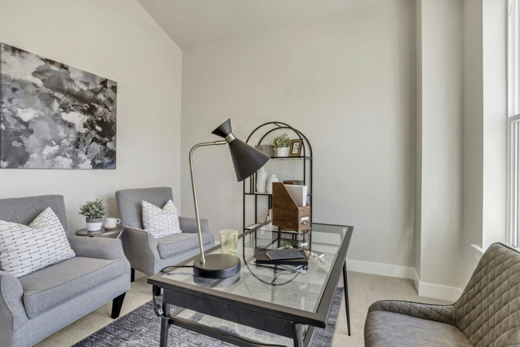 A cozy home office featuring gray chairs and a vibrant painting on the wall, creating a stylish and inviting workspace.